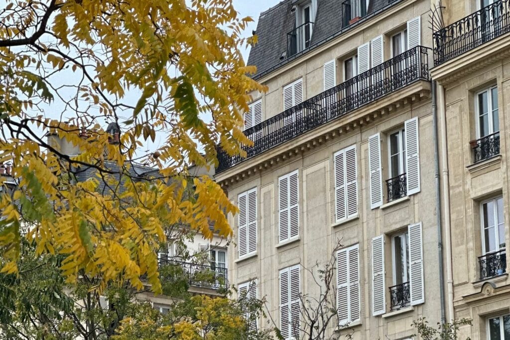Façade haussmannienne aux persiennes claires et toiture en zinc, rive gauche à Paris