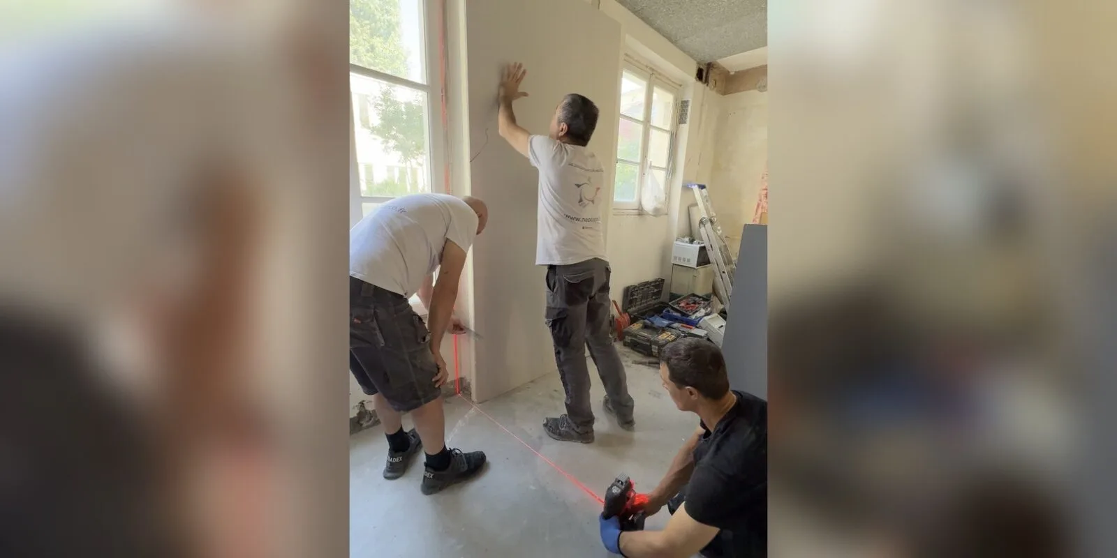 Équipe NEO DECO montant une cloison au niveau laser sur un chantier de rénovation à Paris