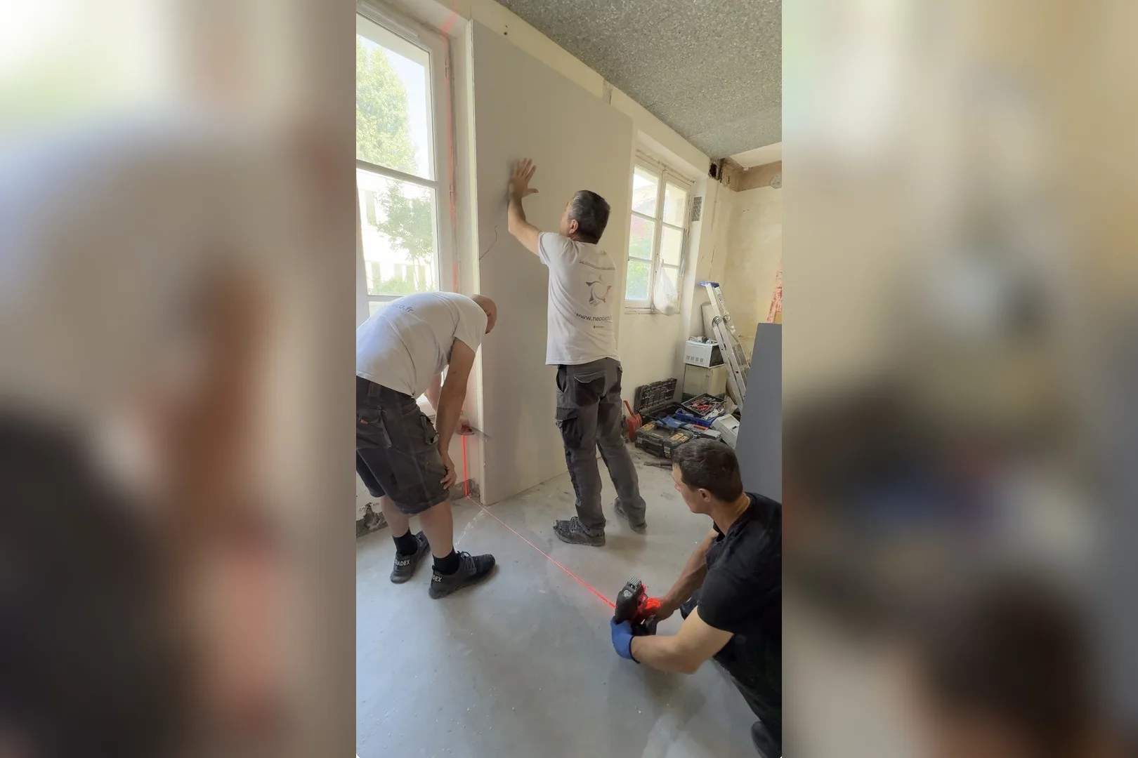 Compagnons montant une cloison au niveau laser avant le passage des gaines électriques